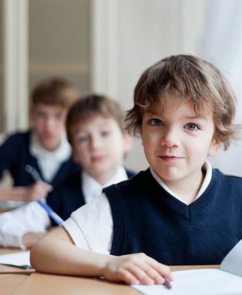 A group of children sitting at desks in front of papers.