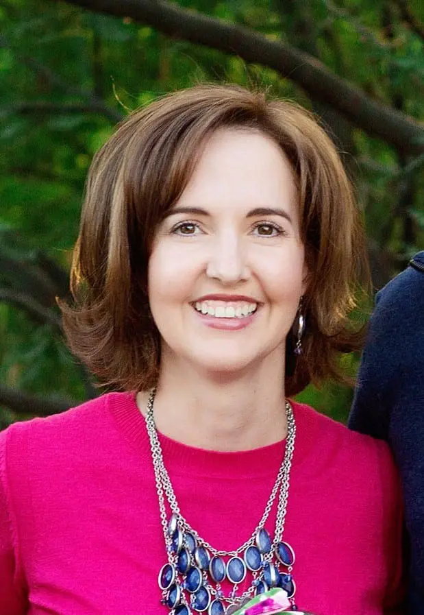 Woman smiling in pink sweater with necklace.